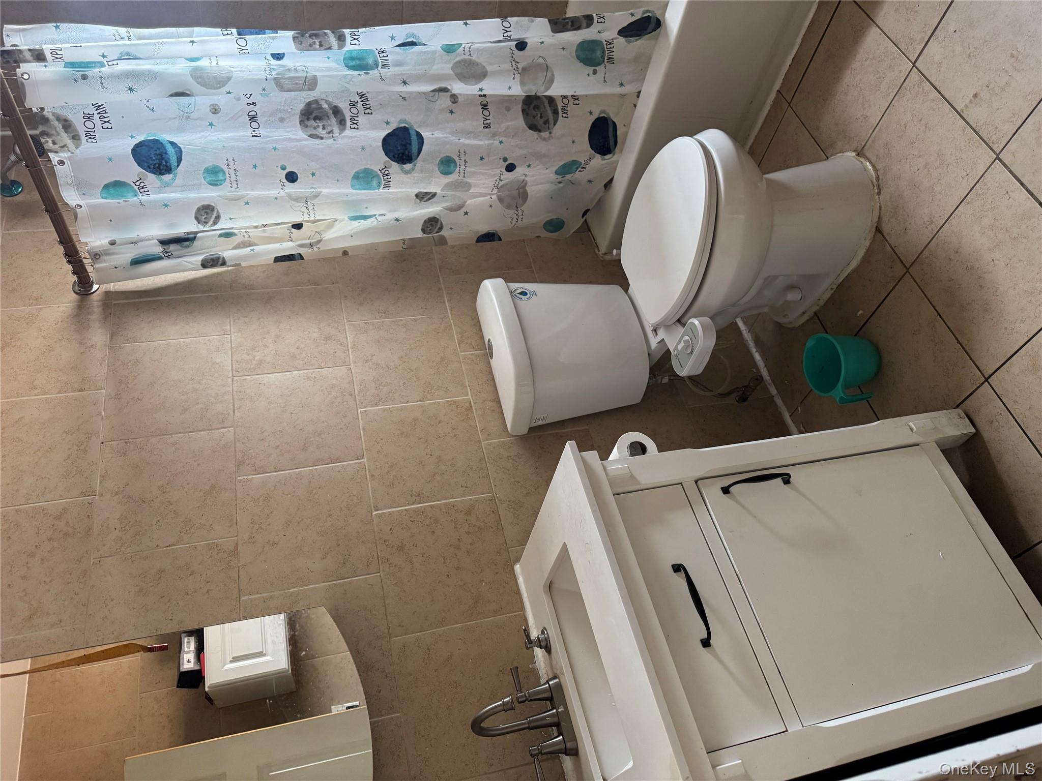 94-13 116th Street Queens, NY 11419 - Photo 27 of 34 Bathroom featuring vanity, shower / tub combo with curtain, tile walls, and light tile patterned flooring
