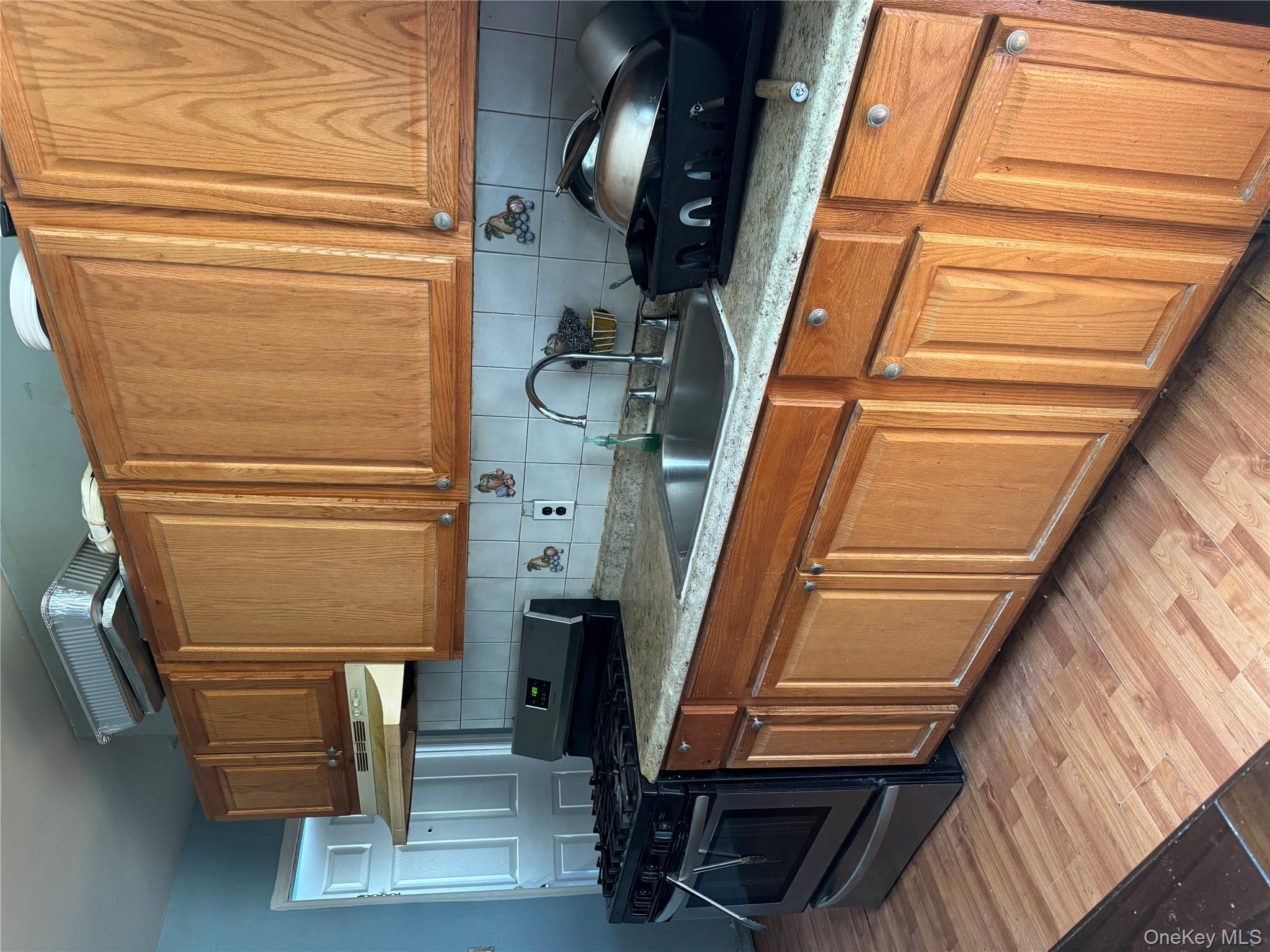 94-13 116th Street Queens, NY 11419 - Photo 28 of 34 Kitchen with backsplash, stove, brown cabinets, and light countertops