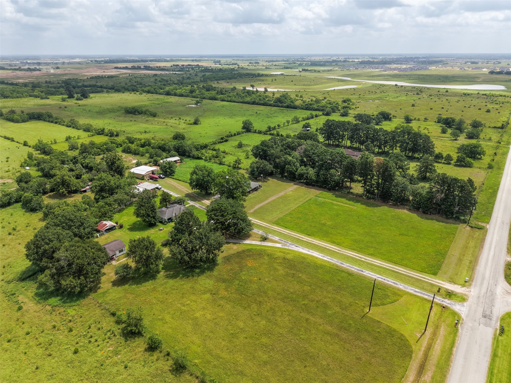 34366 Owens Road Hempstead, TX 77445 - Photo 30 of 46 Expansive aerial view showcasing the home's generous acreage, open pasture, mature trees, outbuildings, and excellent road frontage in a peaceful rural setting.