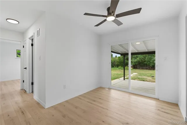 an empty room with wooden floor fan and windows