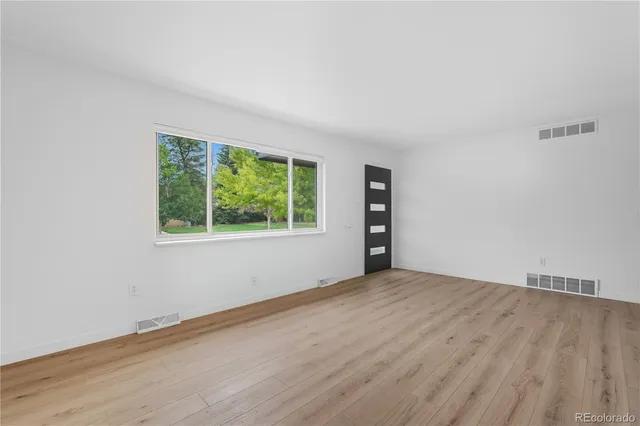 an empty room with wooden floor and windows