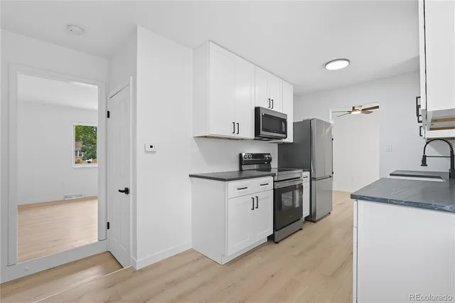 a kitchen with stainless steel appliances granite countertop a refrigerator a stove a sink and white cabinets