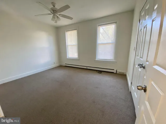 a view of an empty room with chandelier fan