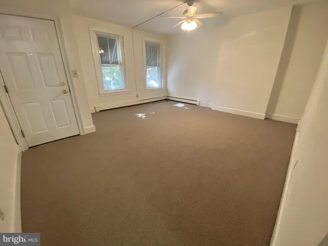 a view of a hallway with wooden floor and a bathroom
