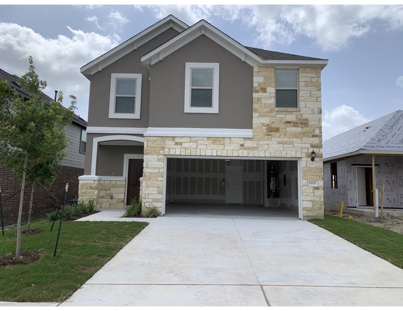 11715 Caithness Way Austin, TX 78653 - Photo 1 of 40 View of front facade with stone siding, stucco siding, concrete driveway, an attached garage, and a front yard