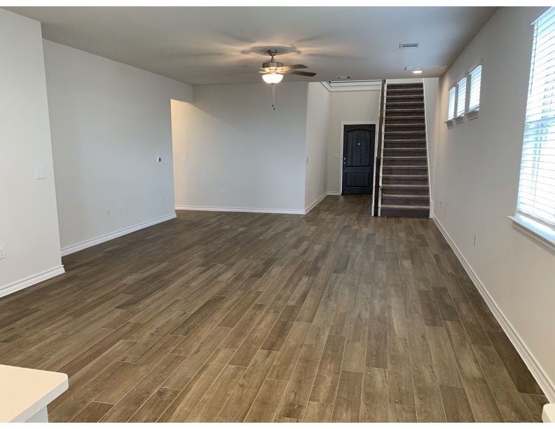 11715 Caithness Way Austin, TX 78653 - Photo 12 of 40 Unfurnished living room and dinner area featuring dark wood finished tile floors and a ceiling fan