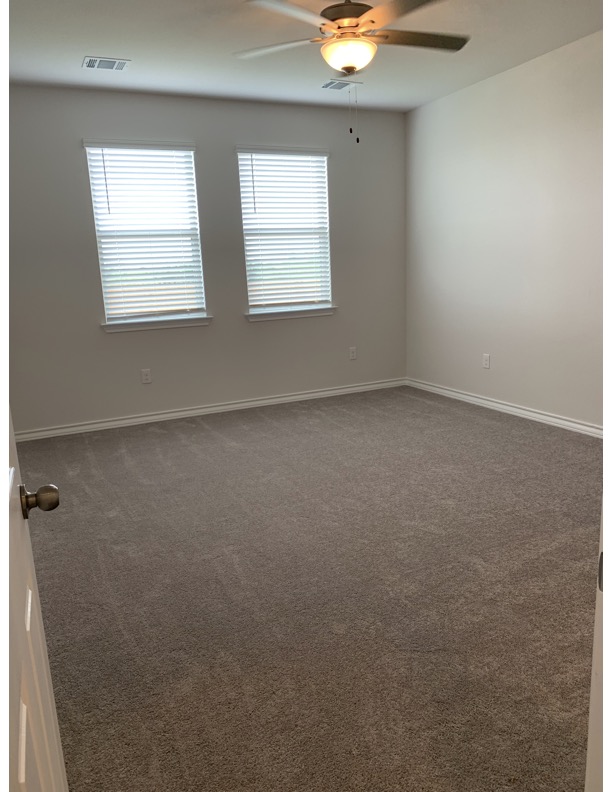 11715 Caithness Way Austin, TX 78653 - Photo 30 of 40 Unfurnished primary bedroom downstairs with ceiling fan and dark colored carpet