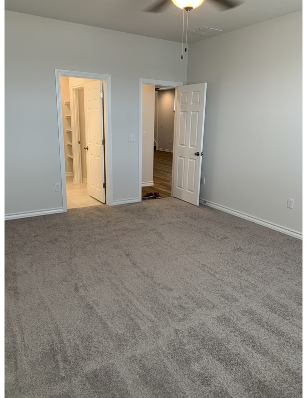 11715 Caithness Way Austin, TX 78653 - Photo 31 of 40 Unfurnished primary bedroom downstairs featuring light carpet and a ceiling fan