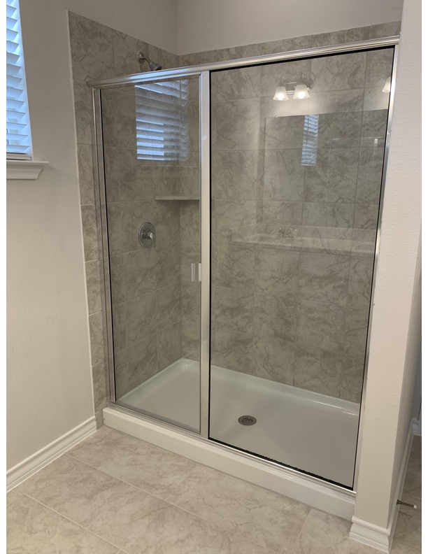 11715 Caithness Way Austin, TX 78653 - Photo 34 of 40 Primary bathroom with a shower stall and light tile patterned flooring