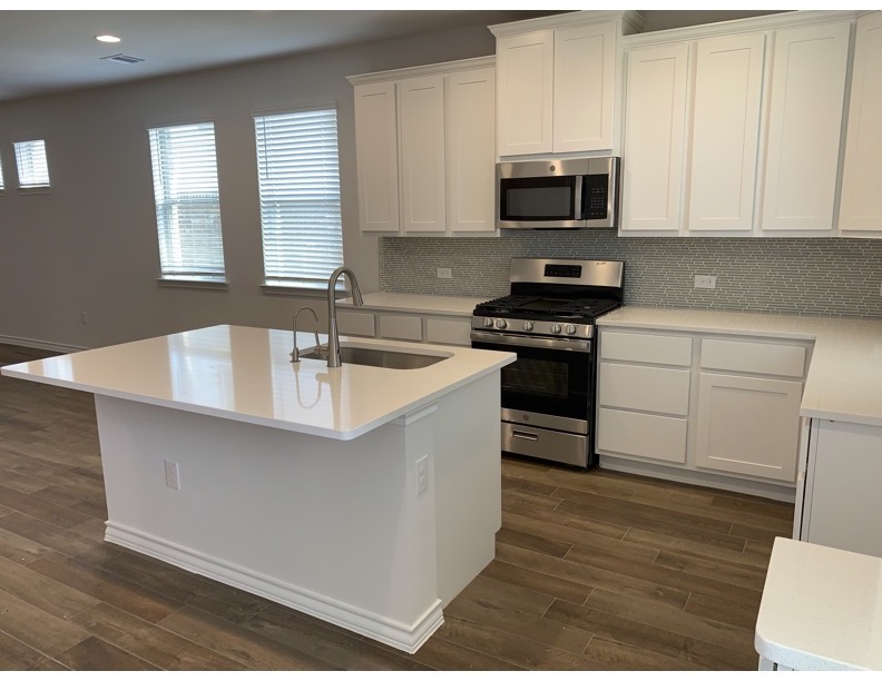 11715 Caithness Way Austin, TX 78653 - Photo 6 of 40 Kitchen featuring stainless steel appliances, white cabinetry, backsplash, a kitchen island with sink, and recessed lighting