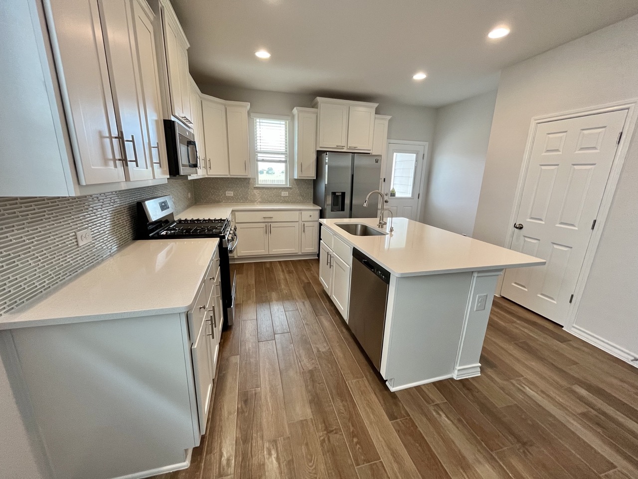 11715 Caithness Way Austin, TX 78653 - Photo 8 of 40 Kitchen with stainless steel appliances, white cabinets, dark wood finished floors, recessed lighting, and decorative backsplash