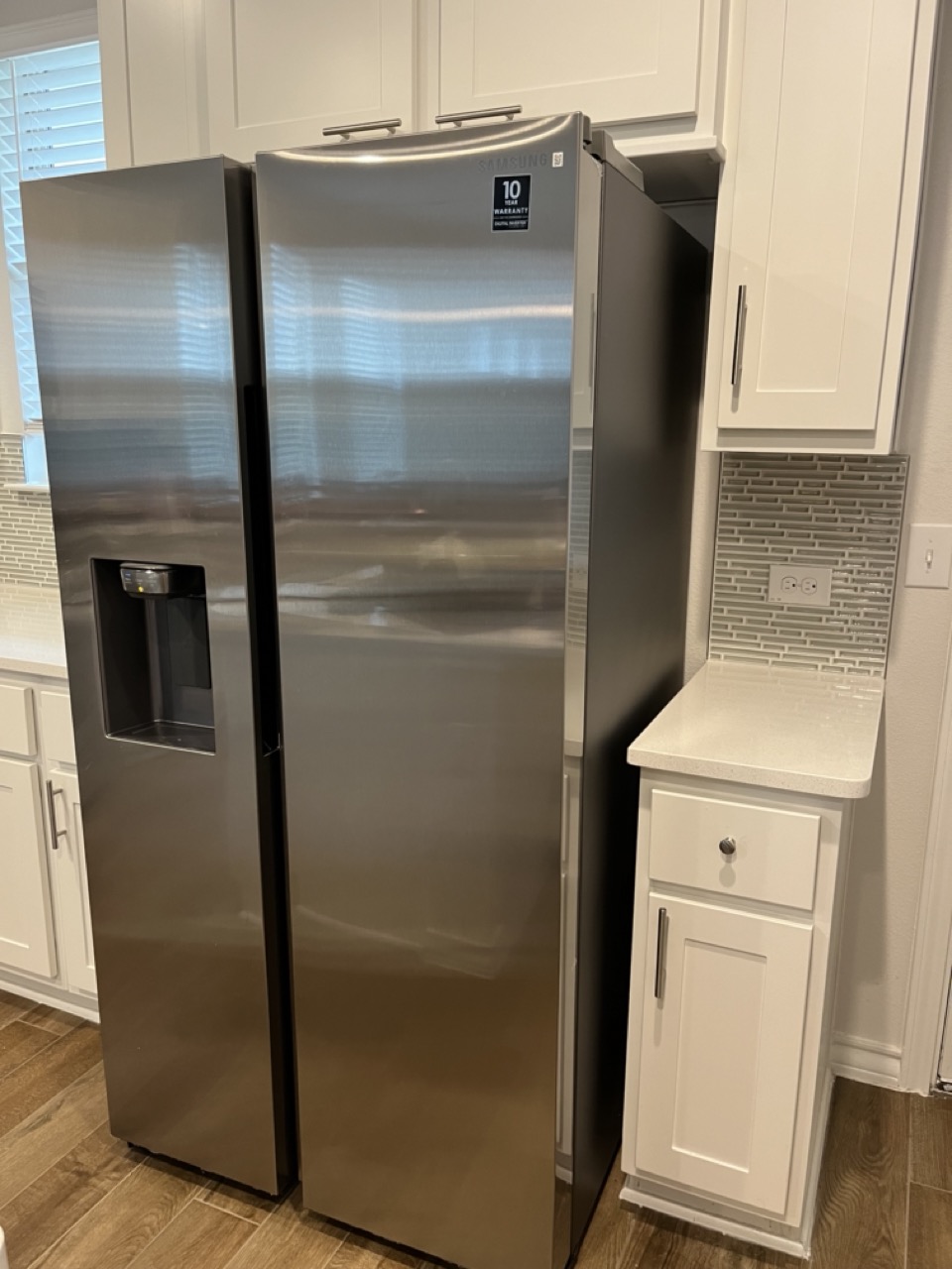 11715 Caithness Way Austin, TX 78653 - Photo 10 of 40 Kitchen with decorative backsplash, dark wood-style floors, stainless steel fridge, and white cabinetry