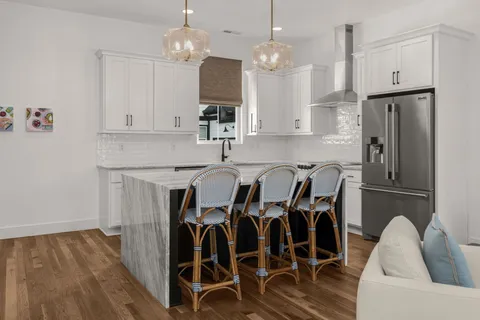 a kitchen with stainless steel appliances granite countertop a dining table chairs refrigerator and microwave