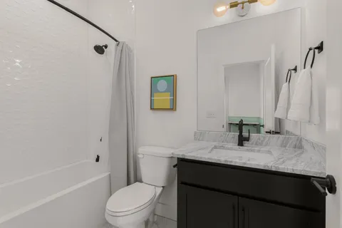 a bathroom with a granite countertop sink toilet and shower