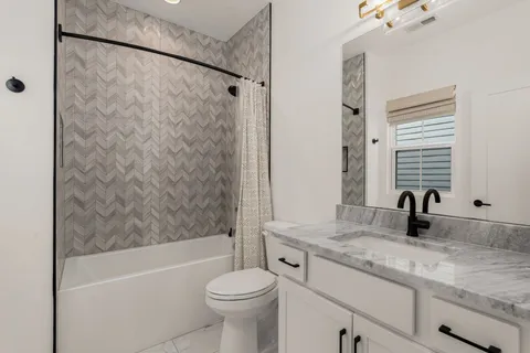 a bathroom with a granite countertop sink toilet mirror and bathtub