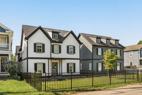 a view of a white house with large windows and a table and chairs