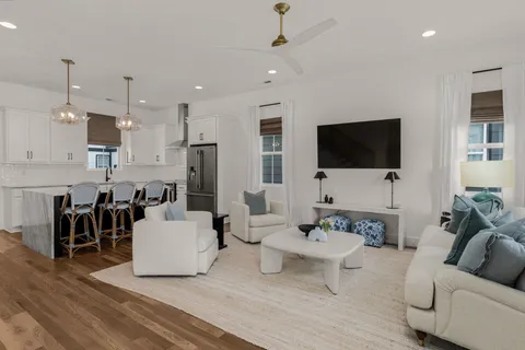 a living room with furniture a flat screen tv and kitchen view