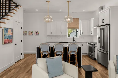 a kitchen with stainless steel appliances granite countertop a refrigerator a sink dishwasher a dining table and chairs with wooden floor