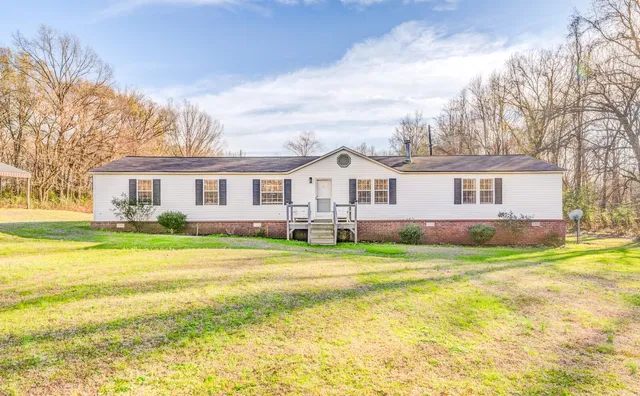 a view of a house with a big yard and large trees