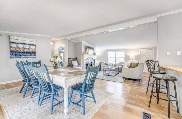a view of a dining room and livingroom with furniture wooden floor a rug and a painting