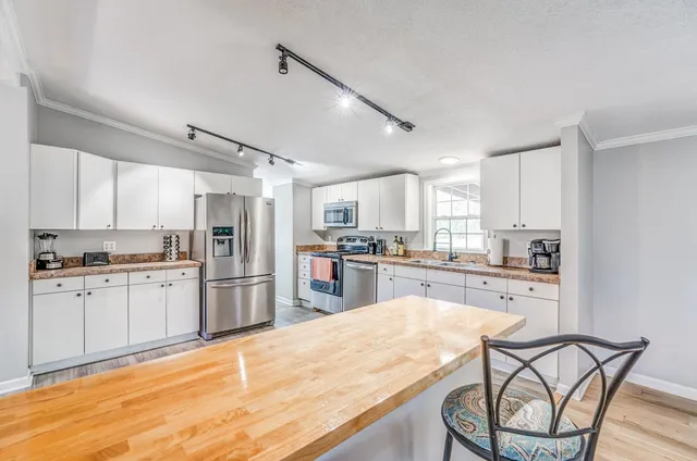 a kitchen with granite countertop refrigerator cabinets dining table and chairs