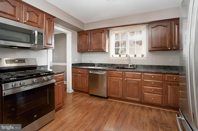 a kitchen with stainless steel appliances granite countertop a stove a sink and a microwave