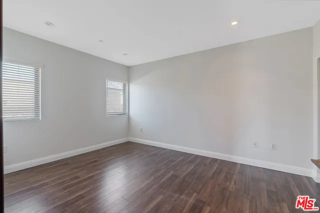 a view of an empty room with wooden floor and closet
