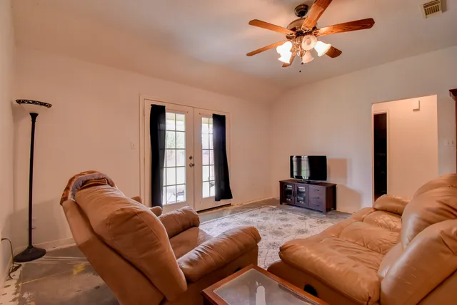 a living room with furniture a ceiling fan and a flat screen tv