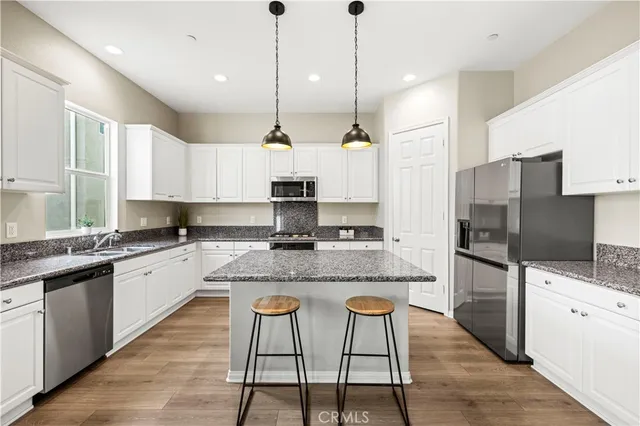 a large kitchen with stainless steel appliances kitchen island granite countertop a sink a stove a refrigerator and cabinets