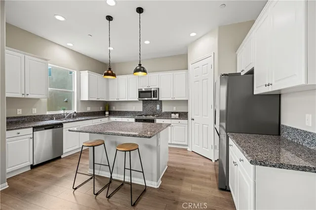 a kitchen with stainless steel appliances granite countertop a sink a stove a refrigerator and island