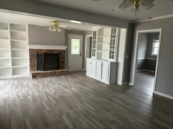 an empty room with wooden floor fireplace and windows