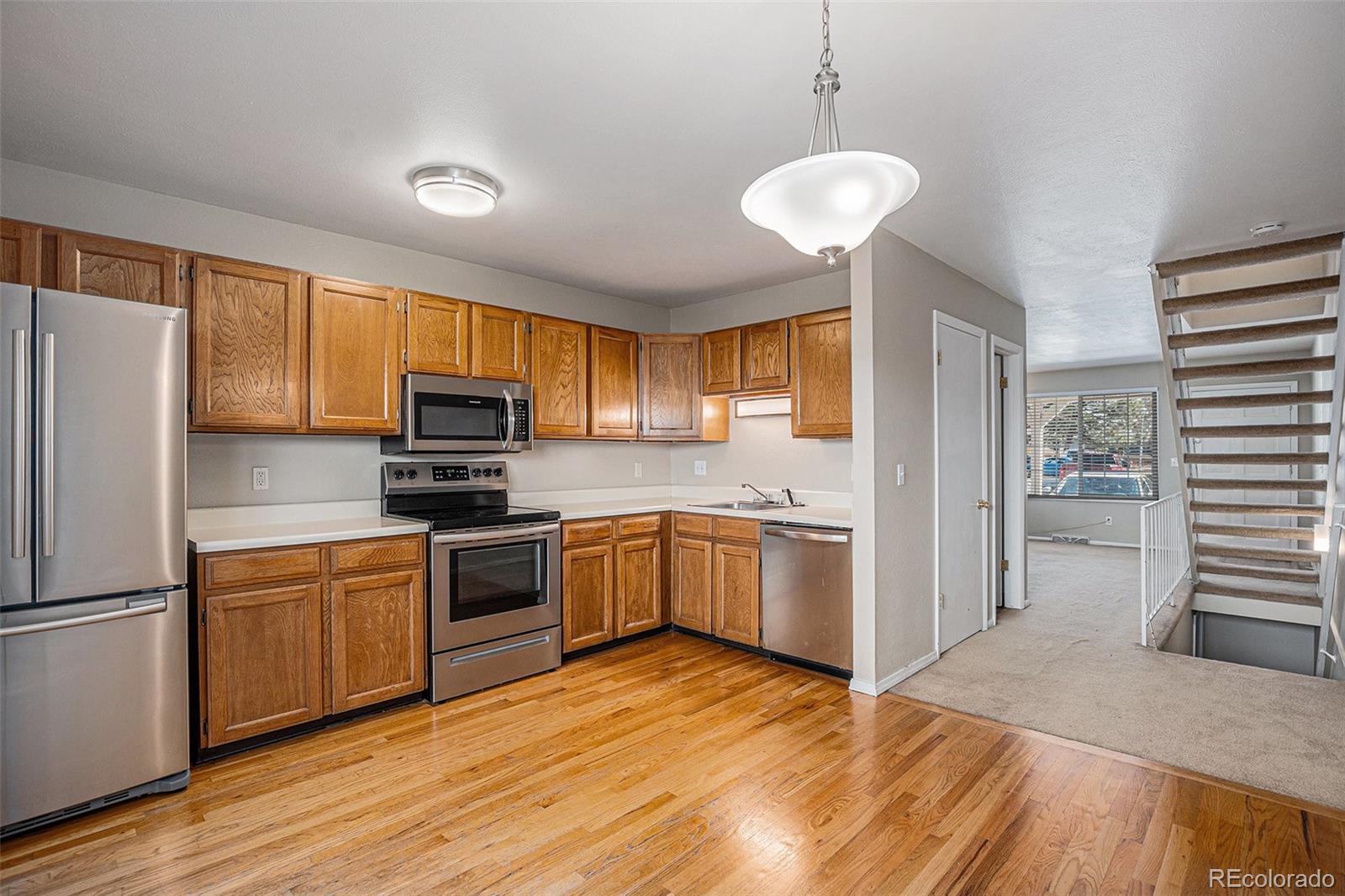 8915 Field Street, Unit 113 Westminster, CO 80021 - Photo 5 of 38 a kitchen with a refrigerator a stove top oven a sink dishwasher and wooden cabinets