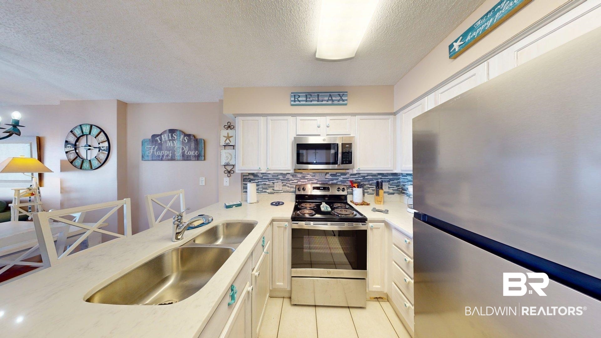 645 Plantation Road, Unit 6503 Gulf Shores, AL 36542 - Photo 25 of 53 Kitchen featuring appliances with stainless steel finishes, a textured ceiling, tasteful backsplash, white cabinetry, and light tile patterned floors
