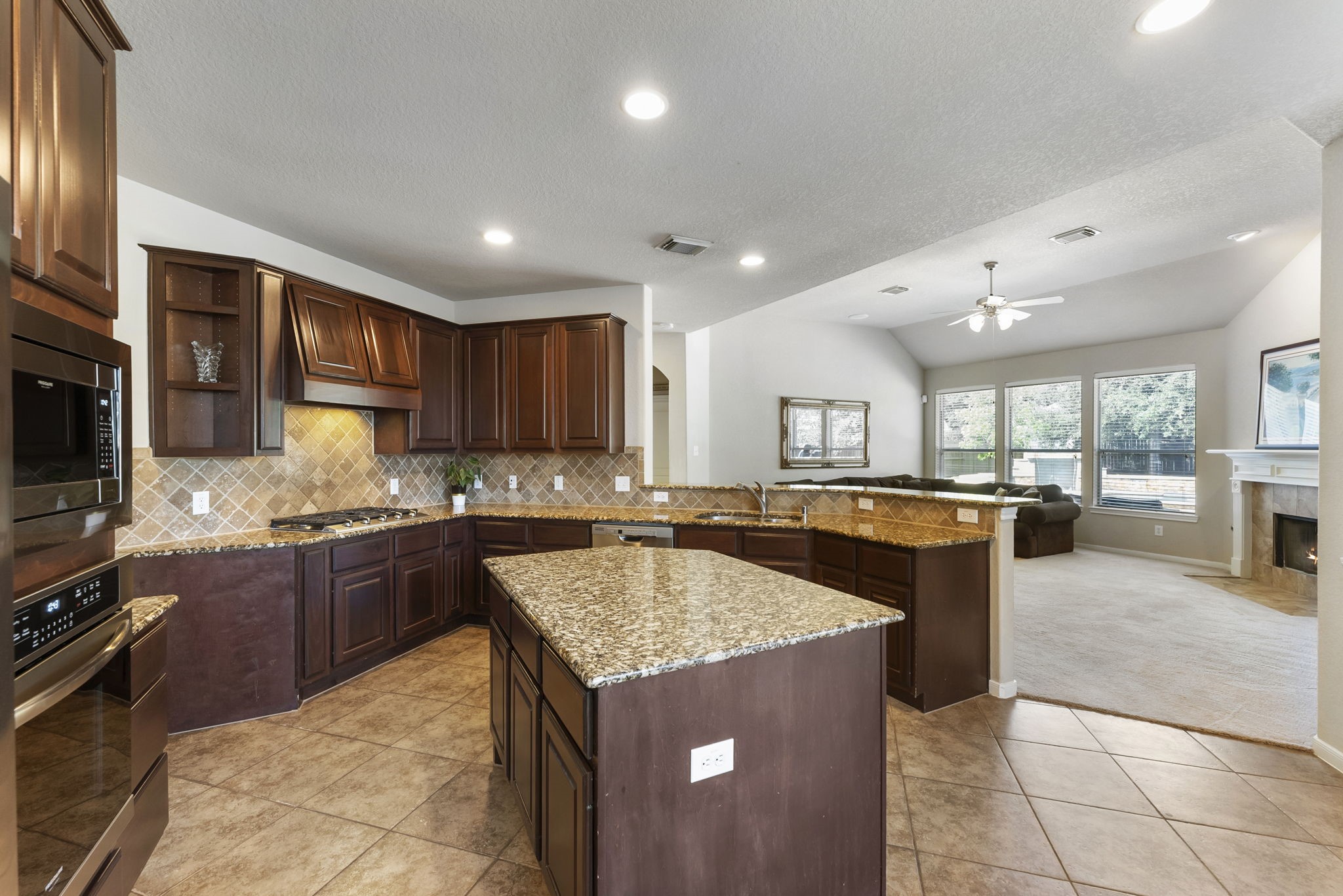 19223 Senterra Lakes Boulevard Spring, TX 77379 - Photo 25 of 48 a kitchen with stainless steel appliances granite countertop a stove top oven a sink dishwasher a dining table and chairs with wooden floor