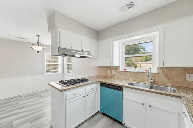 a kitchen with granite countertop a sink a stove cabinets and window