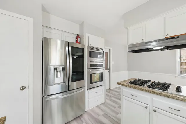 a kitchen with stainless steel appliances granite countertop a refrigerator and a stove top oven