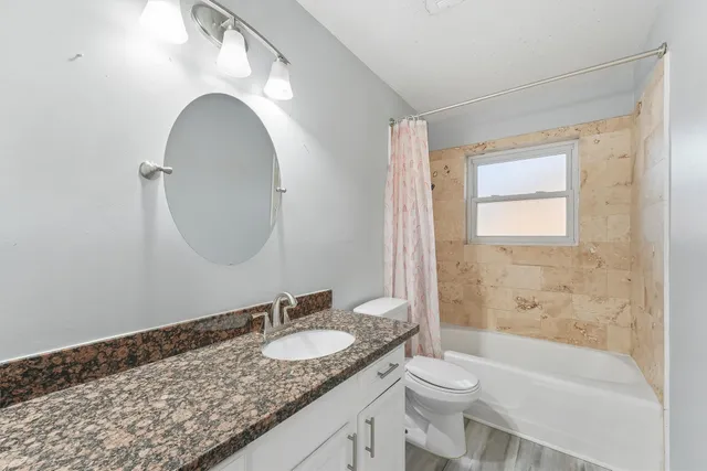 a bathroom with a granite countertop sink toilet and shower