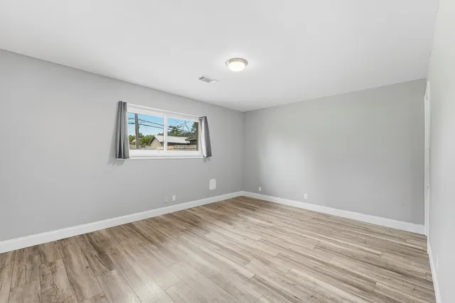 a view of empty room with wooden floor and fan