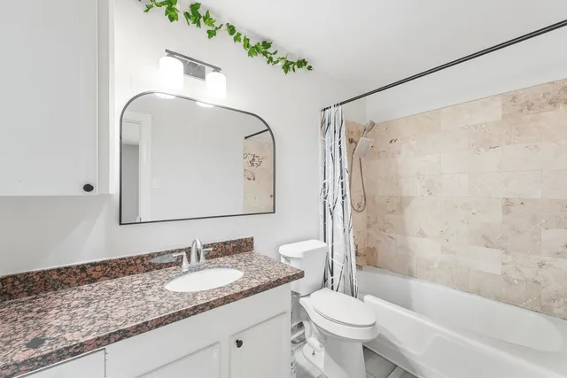 a bathroom with a granite countertop sink toilet mirror and shower