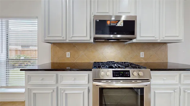 a kitchen with granite countertop white cabinets and stainless steel appliances