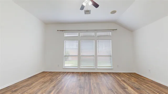 an empty room with wooden floor cabinet and windows