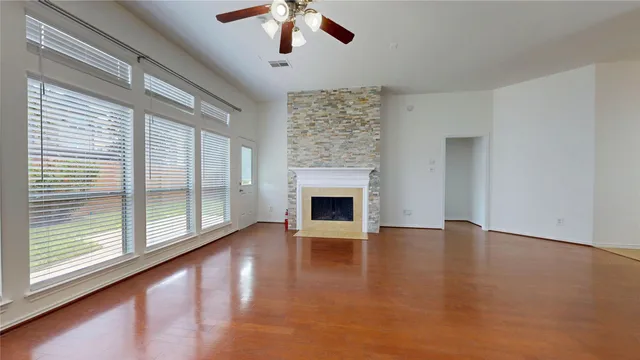an empty room with fireplace fan and windows