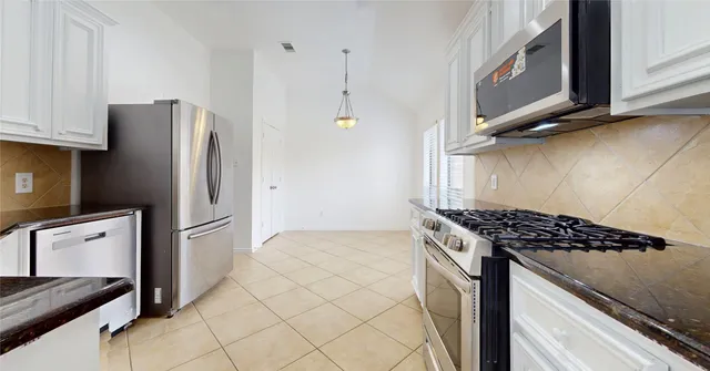 a kitchen with granite countertop a refrigerator and a stove