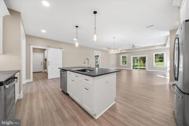 a kitchen with stainless steel appliances granite countertop a sink a stove and a wooden floors