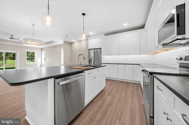 a large kitchen with granite countertop a sink a counter space appliances and cabinets