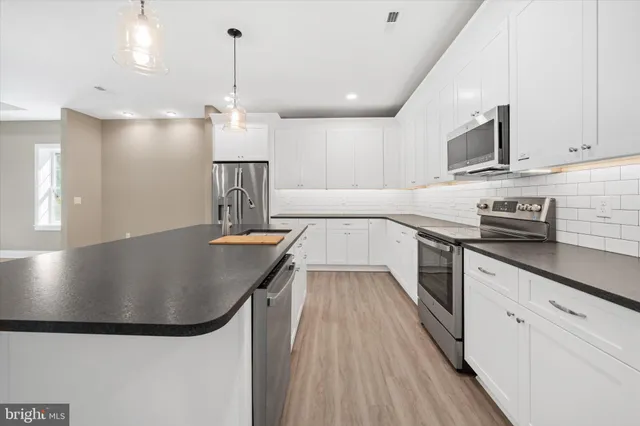 a kitchen with stainless steel appliances granite countertop a sink a stove and a wooden floors