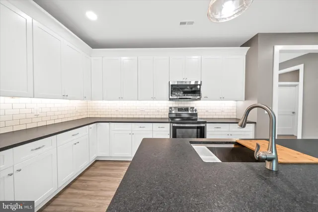 a kitchen with kitchen island granite countertop a sink stainless steel appliances and cabinets