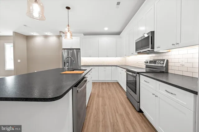 a kitchen with stainless steel appliances granite countertop a sink a stove and a wooden floors