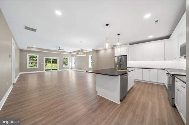 a kitchen with stainless steel appliances granite countertop a stove and a wooden floors