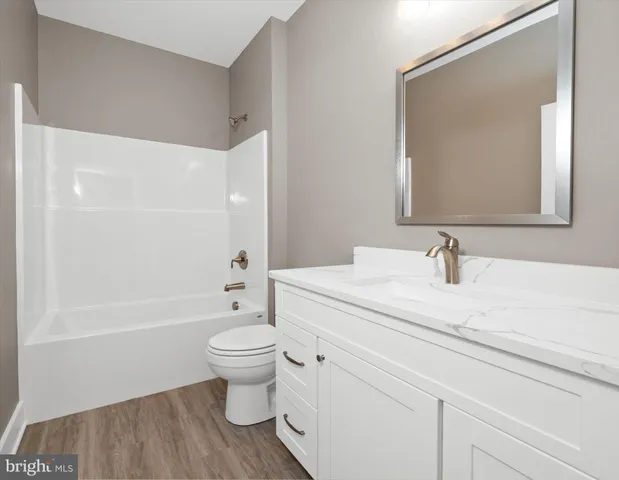 a bathroom with a granite countertop sink a toilet and a large mirror